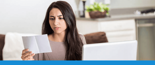 A woman looking at her medical bills from having to get treatment for migraines