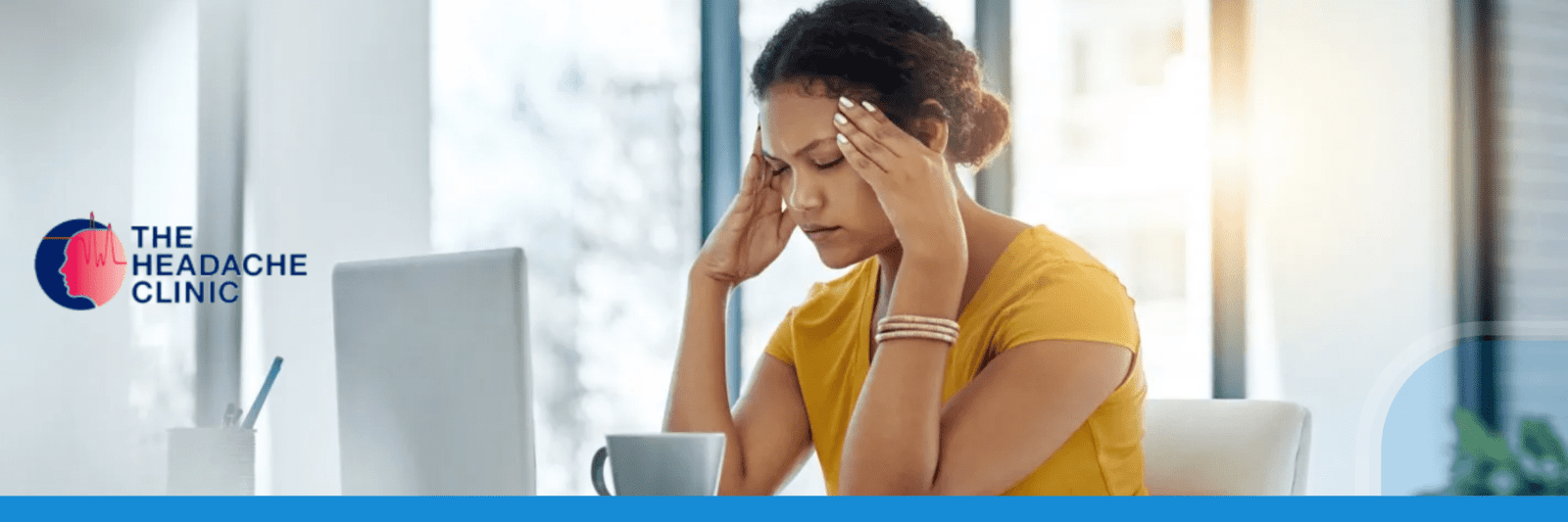 A woman at holding her head at work during a migraine episode